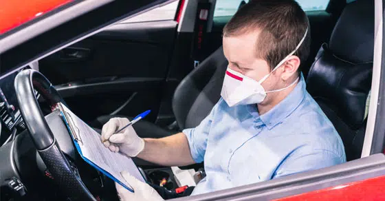 Man in mask signing paperwork in his car